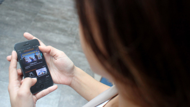 Pengguna ponsel pintar atau smartphone sedang menonton streaming video.