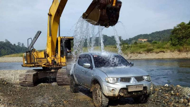 Mobil kabin ganda diguyur air dari ekskavator