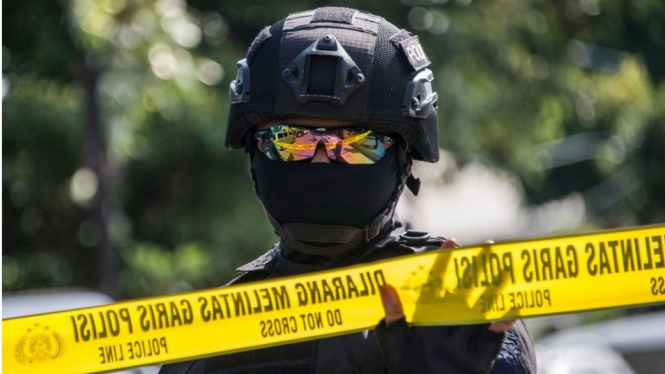 Seorang polisi menjaga kamar jenazah yang menyimpan jenazah terduga pelaku penyerangan tiga gereja di Surabaya, 13 Mei lalu. - AFP/Getty Images
