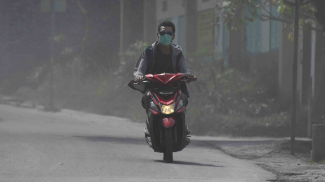 Pengendara sepeda motor mengenakan masker.