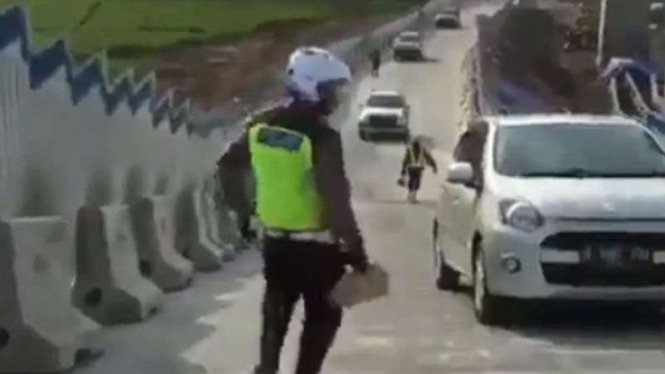 Polisi berusaha membantu mobil yang mundur lagi di tanjakan Tol Salatiga.
