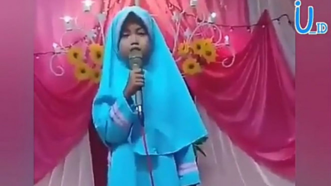 Anak perempuan bicara di atas panggung.