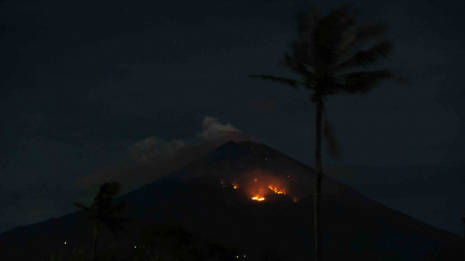 Api membakar hutan lereng Gunung Agung setelah terjadinya lontaran batu pijar dari kawah terlihat dari Desa Culik, Karangasem, Bali