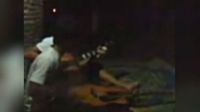 Dua pemuda sedang asyik bermain gitar.
