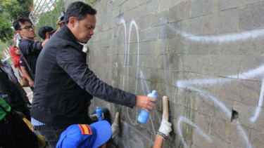Wali Kota Bogor Bima Arya membersihkan tembok Kebun Raya Bogor yamg jadi korban aksi vandalisme.