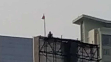 Seseorang panjat baleho depan gedung MPR.