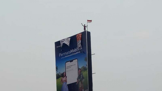 Seseorang panjat baleho depan gedung MPR.