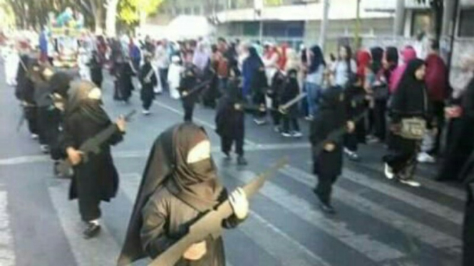 Anak TK mengenakan cadar dan membawa senjata mainan.