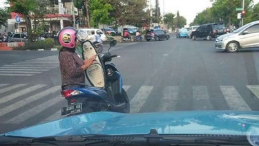 Pengendara wanita bermain ponsel di tengah jalan.