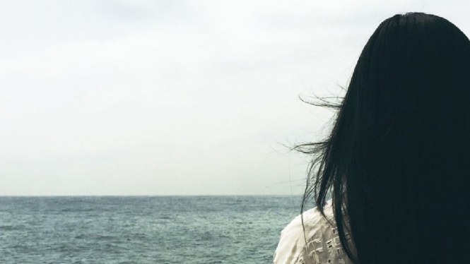 Seorang wanita sedang menatap laut.