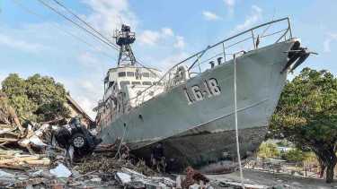 Warga berada di dekat kapal TNI AL yang terdampar di jalanan akibat tsunami di Watusampu, Ulujadi, Palu, Sulawesi Tengah, Kamis, 4 Oktober 2018.