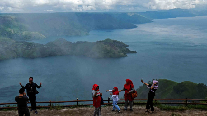 Wisatawan melihat panorama Danau Toba dari puncak 