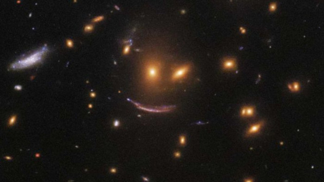 "Bintang tersenyum" yang ternagkap teleskop Hubble, disebabkan oleh cahaya yang melintasi suatu objek besar dengan daya gravitasi tinggi sehingga membuatnya melengkung.