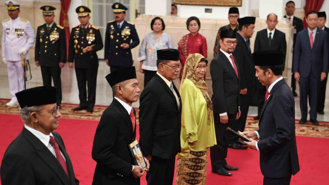 Presiden Joko Widodo (kanan) memberikan tanda jasa kepada ahli waris saat penganugerahan gelar pahlawan nasional di Istana Negara, Jakarta