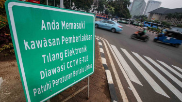 Pengendara melintas di dekat rambu tilang elektronik di Jalan Medan Merdeka Barat, Jakarta