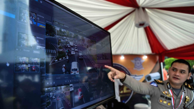 Petugas Ditlantas Polda Metro Jaya menjelaskan sistem tilang elektronik kepada warga saat Grand Launching Electronic Traffic Law Enforcement (E-TLE) di kawasan Bundaran HI, Jakarta