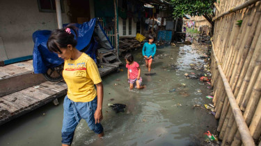 Warga berjalan melintasi banjir rob yang menggenangi Kampung Nelayan Muara Angke di Penjaringan, Jakarta, Senin, 26 November 2018.