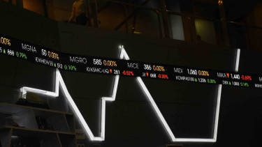 Pegawai melintas di dekat layar pergerakan saham di Bursa Efek Indonesia, Jakarta