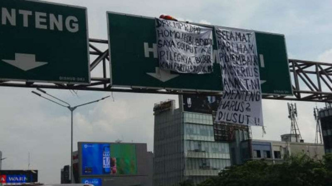 Agustinus Woro, pria yang sering memanjat baliho, naik ke papan penunjuk jalan
