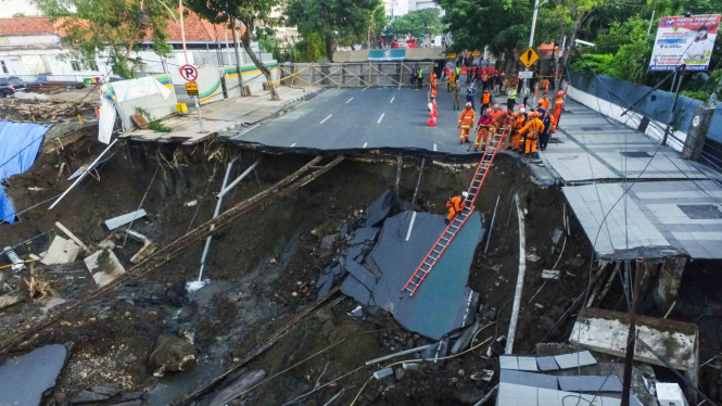 Sejumlah petugas pemadam kebakaran memeriksa kondisi tanah ambles di Jalan Raya Gubeng, Surabaya, Jawa Timur, Rabu, 19 Desember 2018.