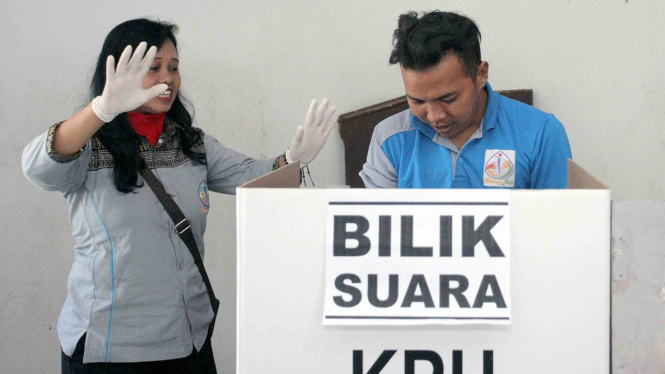 Petugas KPPS membantu seorang penyandang disabilitas Orang Dengan Gangguan Jiwa (ODGJ) membuka surat suara di bilik suara saat simulasi pemilu bagi ODGJ di Kota Blitar, Jawa Timur.