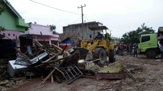 Petugas dengan menggunakan alat berat membersihkan sisa-sisa bangunan yang tersapu tsunami di jalan Desa Way Muli, Kecamatan Rajabasa, Lampung Selatan, Lampung