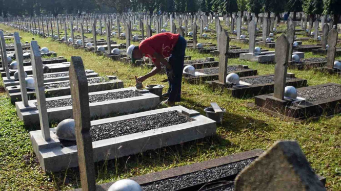 Pekerja memperbaiki makam yang rusak akibat tertimpa pohon di Taman Makam Pahlawan Kalibata, Jakarta