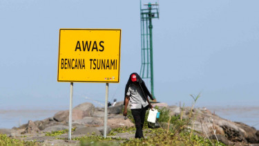 Warga berjalan di dekat rambu peringatan bencana tsunami.