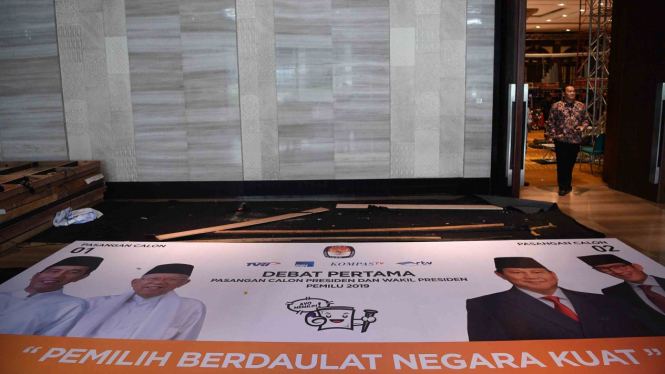 Petugas keamanan melintas di dekat spanduk yang dipersiapkan untuk debat pertama capres-cawapres Pilpres 2019 di Hotel Bidakara, Jakarta Selatan, Rabu, 16 Januari 2019.