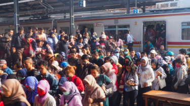 Sejumlah penumpang berjalan menyeberangi perlintasan jalur kereta.