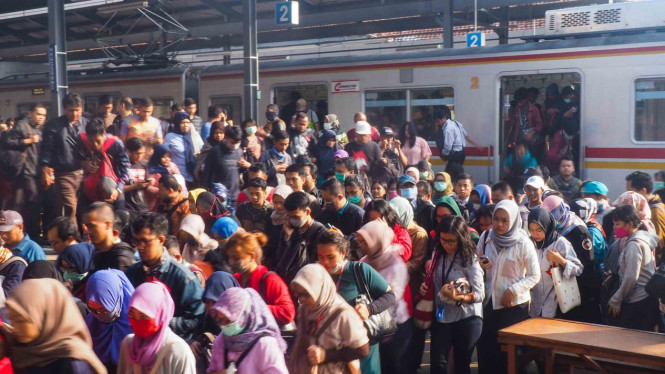 Sejumlah penumpang berjalan menyeberangi perlintasan jalur kereta.