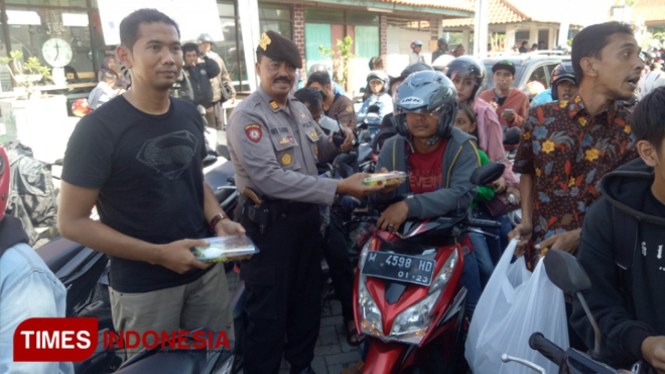 Kapolsek Kamal AKP Abd Kadir bersama Camat Kamal Akhmad Ahadiyan Hamid membagikan nasi dan air mineral gratis kepada pengendara di Pelabuhan Kamal. (FOTO: Doni Heriyanto/TIMES Indonesia)