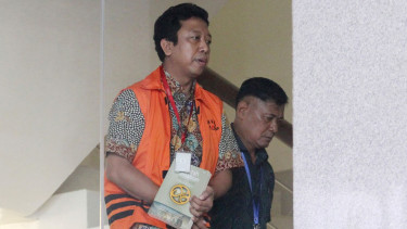 Romahurmuziy alias Rommy menutupi tangannya yang diborgol dengan buku.