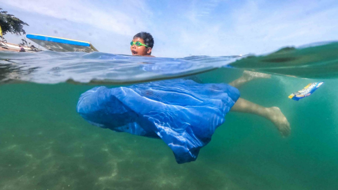 Seorang anak berenang di dekat sampah plastik yang hanyut terbawa arus di pantai wisata Senggigi, Lombok Barat, NTB