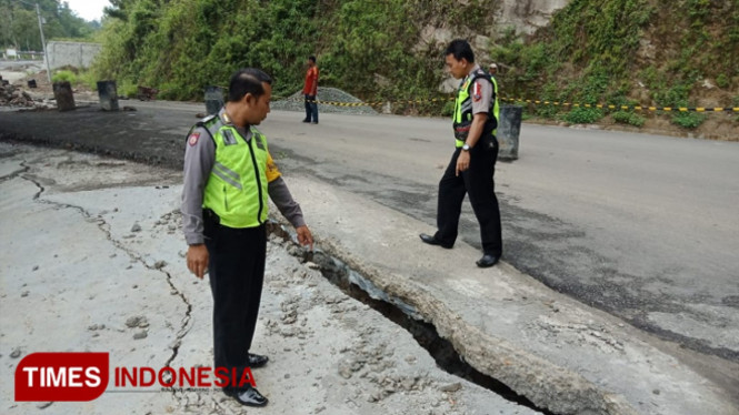 Petugas dari Polsek Slahung menunjukkan bagian jalan yang retak dan amblas. (Foto: Evita Mukharohmah)