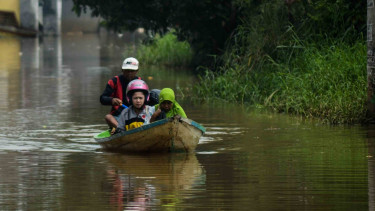 Warga menggunakan perahu untuk melintasi jalan yang tergenang banjir di Andir, Dayeuhkolot Kabupaten Bandung, Jawa Barat, Selasa, 16 April 2019.