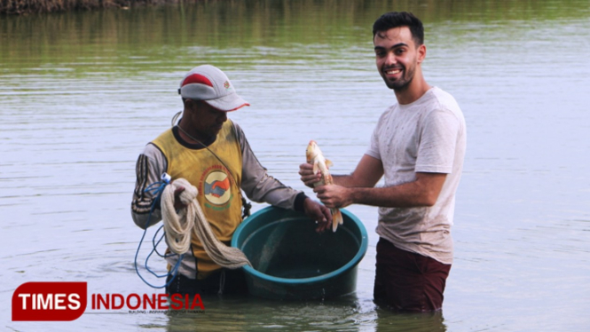 Joel ikut memanen ikan bandeng si lahan tambak (FOTO: Akmal/TIMES Indonesia).