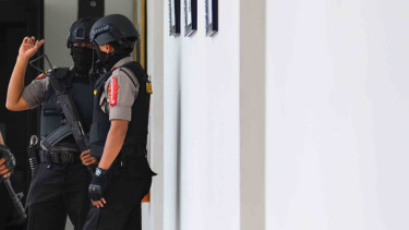Personel polisi berjaga saat penggeledahan. 
