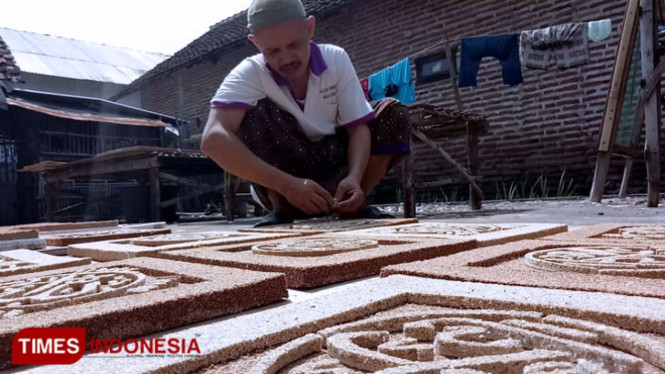 Kholili pengrajin kaligrafi berbahan dasar dari serbuk kayu, saat proses pembuatan kaligrafi di rumahnya.(FOTO: Dicko W/TIMES Indonesia)