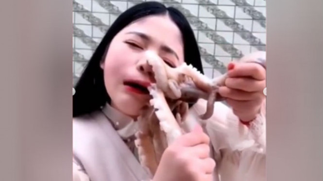 Wanita makan gurita hidup-hidup.