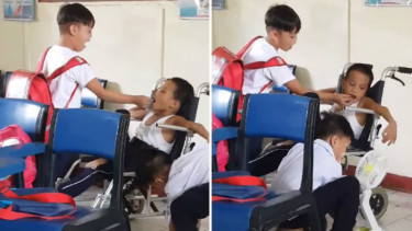 Dua siswa membantu temannya yang disabilitas