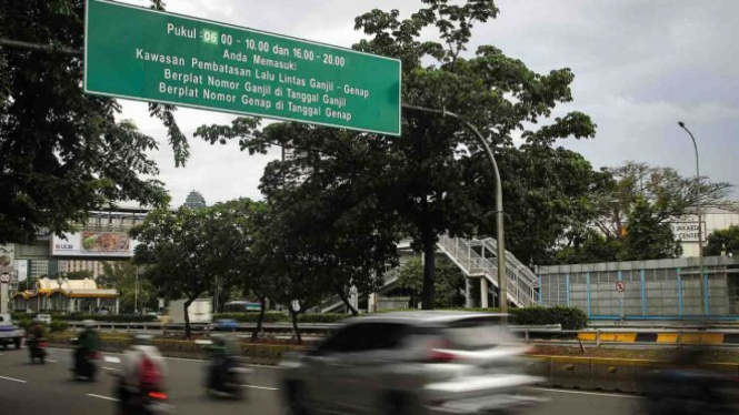 Kendaraan melintasi papan informasi penerapan sistem ganjil genap di Jakarta