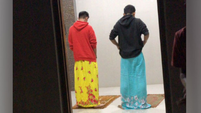 Pria salat pakai mukena.