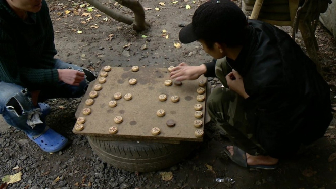 The men play games as they wait to make their journey to the UK - BBC