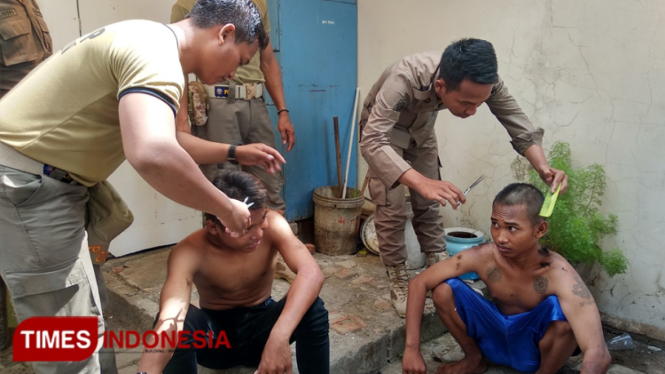 Petugas Satpol PP Tuban saat mencukur rambut Anjal di halaman belakang Dinsos P3A Tuban,Senin, (09/12/2019). (Foto: Achmad Choirudin/TIMES Indonesia)
