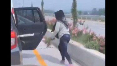 Perempuan memetik bunga di jalan tol