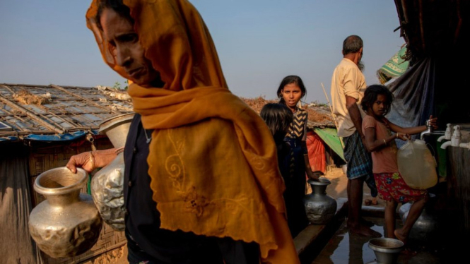 Perempuan Rohingya membawa air dalam kendi alumunium milikknya di kamp pengungsi Jamtoli di Ukhiya, Bangladesh. - K M Asad/Getty