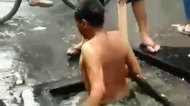 Seorang warga menyelam di gorong-gorong butek di Bandung.