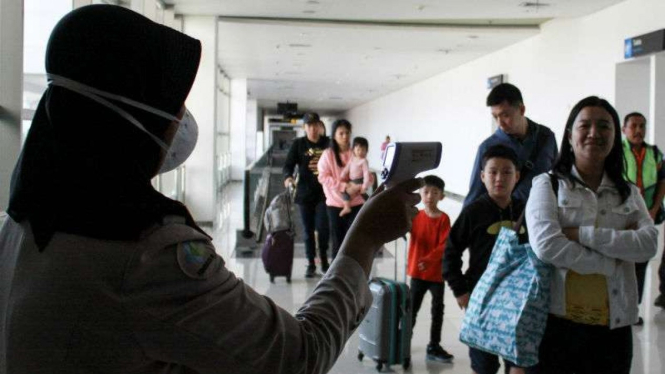 Petugas melakukan pendeteksi suhu tubuh di Bandara Juanda, Surabaya.