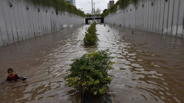 Anak-anak bermain air di underpass Jalan Angkasa yang terendam banjir, Kemayoran, Jakarta Pusat, Selasa (25/2/2020). Hingga Selasa (25/2) sore sejumlah kawasan di Ibu kota masih terendam banjir. 
